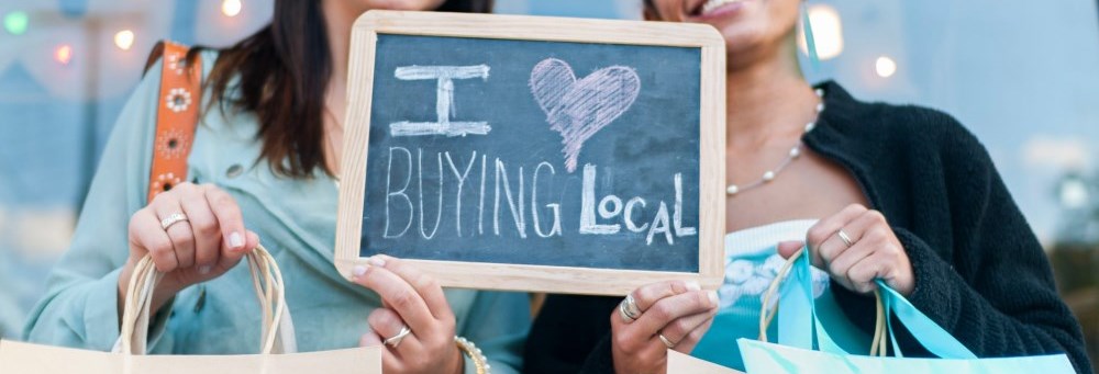 Two people holding an "I Love Buying Local" sign
